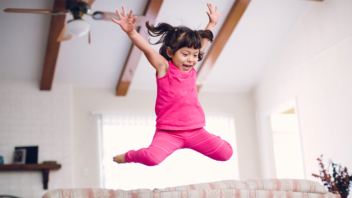 A kid jumping in the air with their arms and legs spread out.