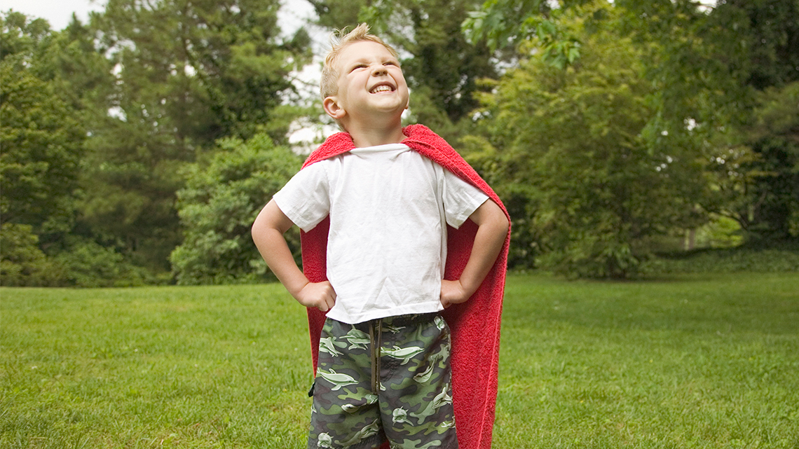 A child standing straight with their hands on their hips, looking up to the sky.