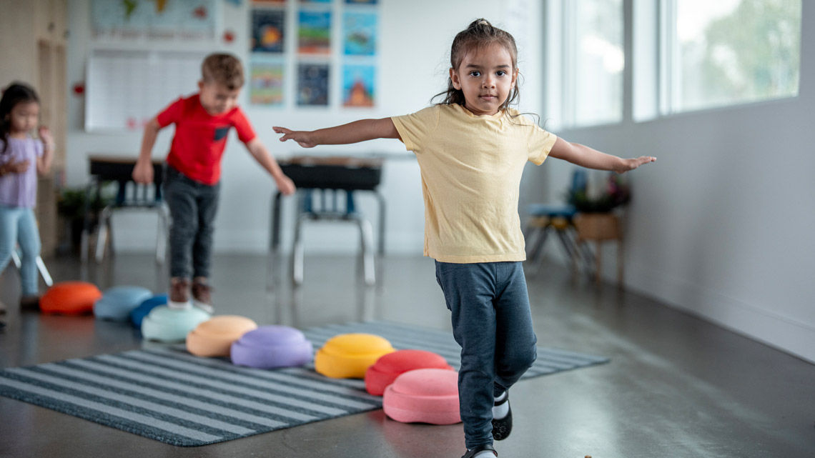 A child balancing on one foot. Their arms are out.