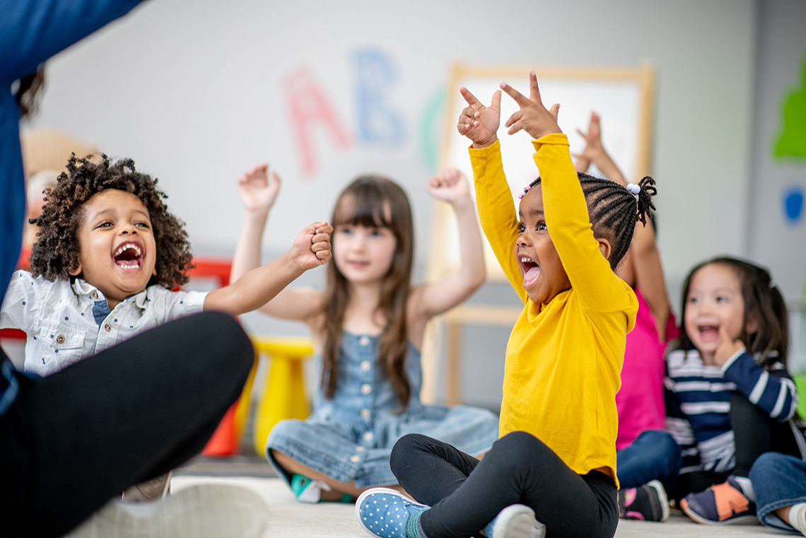 A group of learners sitting with their arms raised up and smiling.