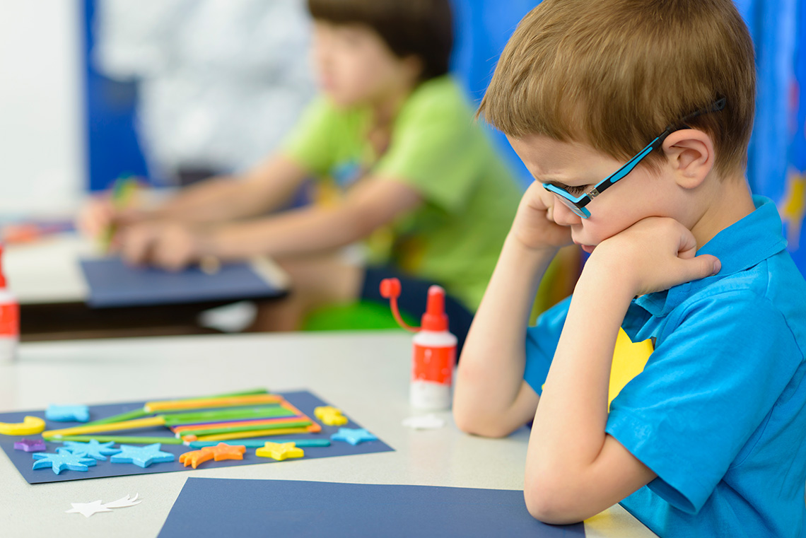 A learner with a frown looking down at their artwork.