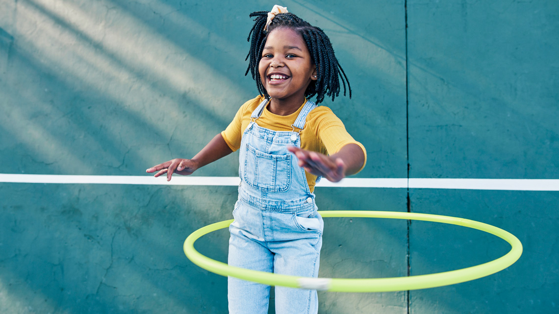 A child smiling using a hula hoop.