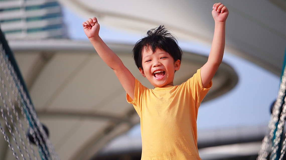 A child is jumping onto a couch. Their arms and legs are spread out. They look excited!