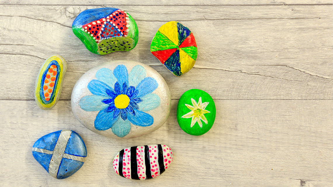 7 painted rocks. One has a flower painted on. The others have patterns on them.