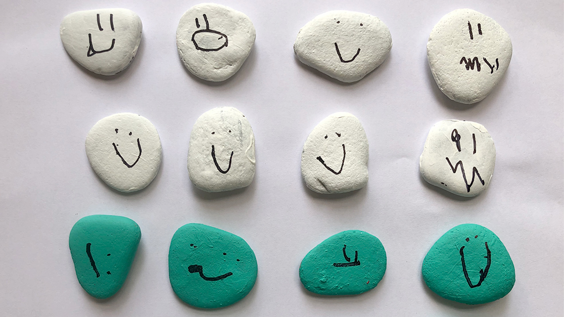 Rocks with faces painted on. Some faces are happy, others are sad, and some are surprised.