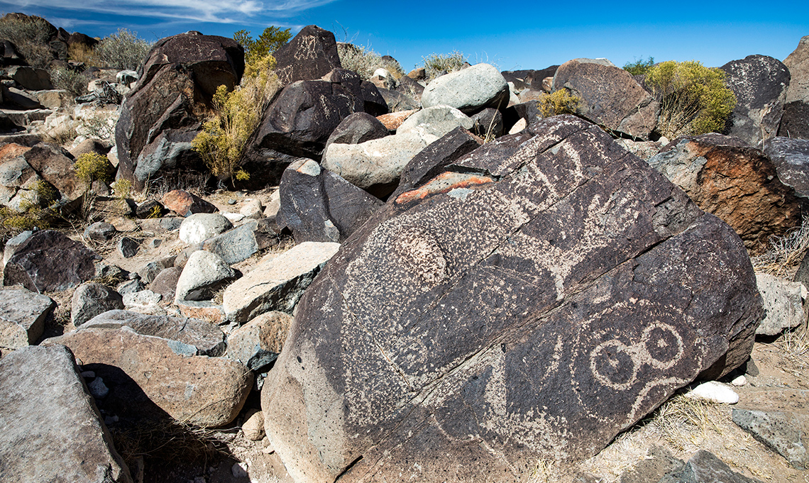 Faces and other drawings are etched in the side of big rocks.