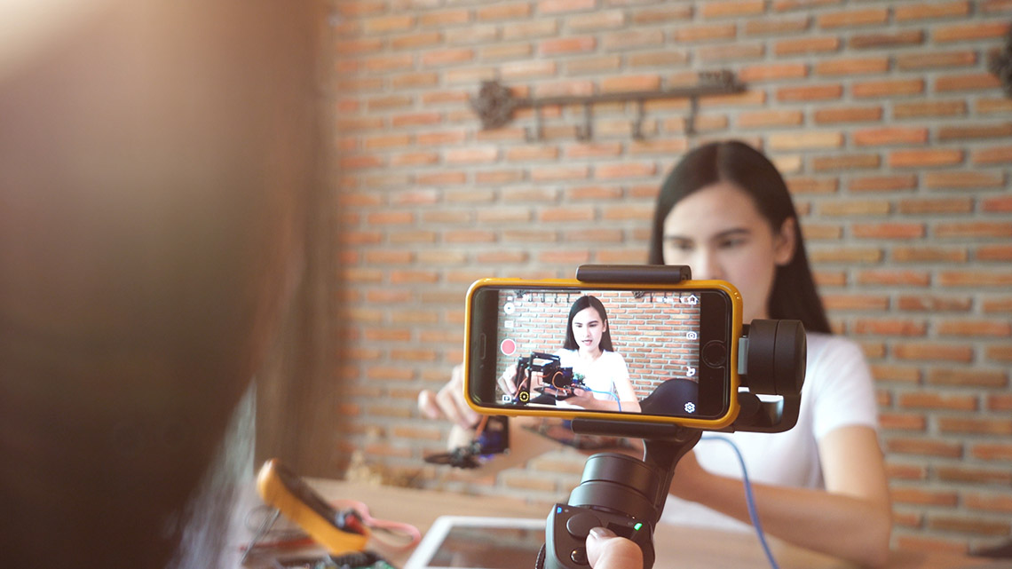 A teenager in a black shirt shooting a video on his phone.