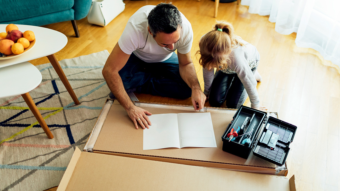 Two people looking at an instruction manual with a box of tools beside them.