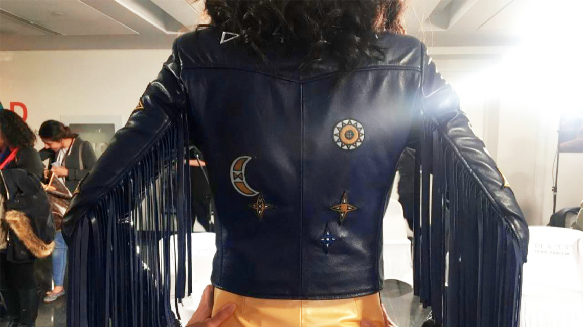 A woman wearing a leather jacket with Indigenous symbols on it.