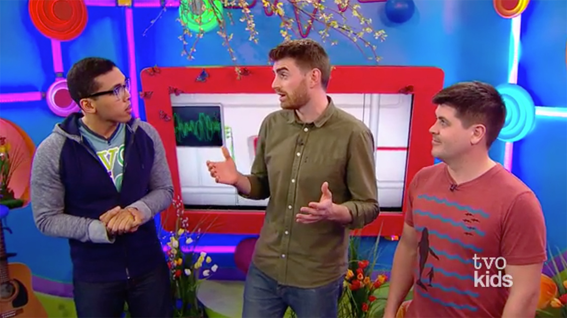 An image of Tyler speaking. Alex faces him and smiles.