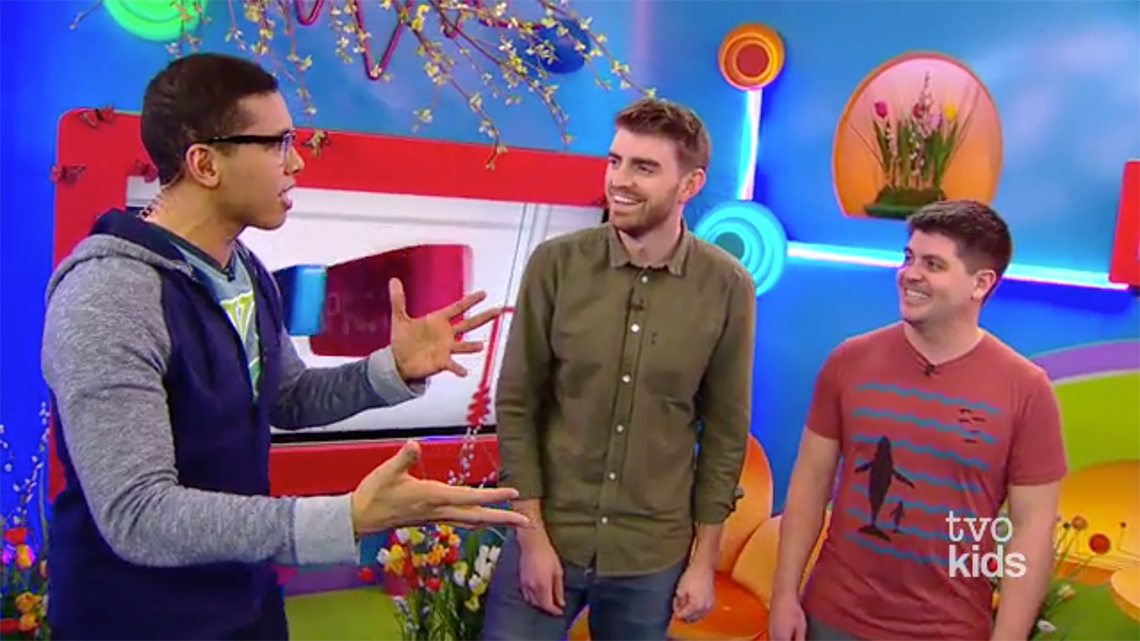 Daniel, Alex, and Tyler at TVOK News. Daniel is speaking and using hand gestures. Alex and Tyler are facing Daniel and smiling.