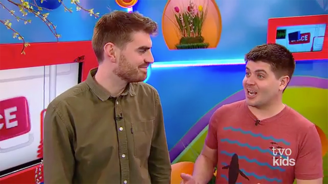 An image of Tyler speaking. Alex faces him and smiles.
