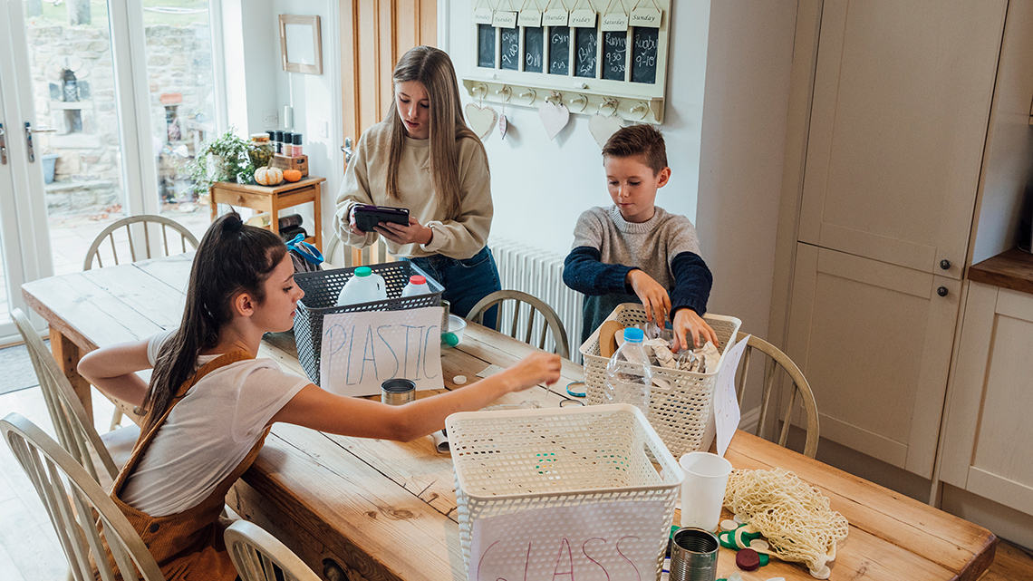 A family working together to recycle paper and bottles in their home.