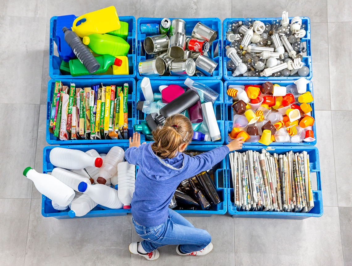 A recycling bin with mixed materials such as plastics, cardboard, glass, aluminum, paper.