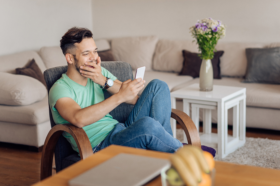 A person sitting on a chair, their mouth is open while holding a phone at eye level.