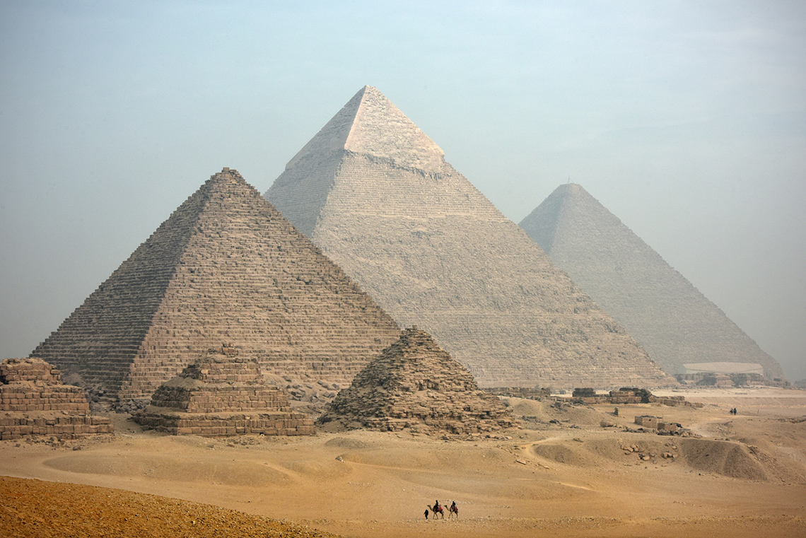 3 large pyramids and 3 smaller ones. In the foreground, a few people are heading toward the pyramids.