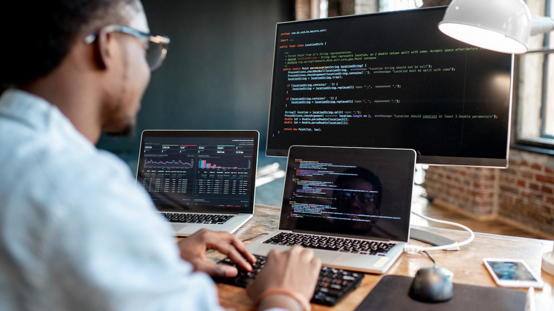 Man working on a computer with multiple monitors.
