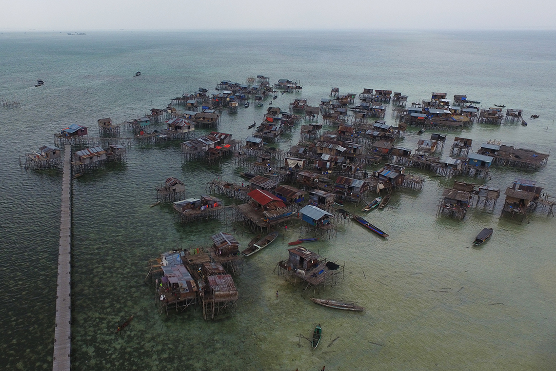 This image is a Bajau community in Malaysia. The village has a few dozen small, wooden homes built on stilts right in the water.