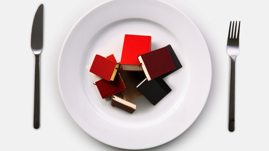A bunch of books on a plate with a knife and fork