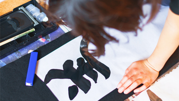 A group of children holding Japanese ink brushes.
