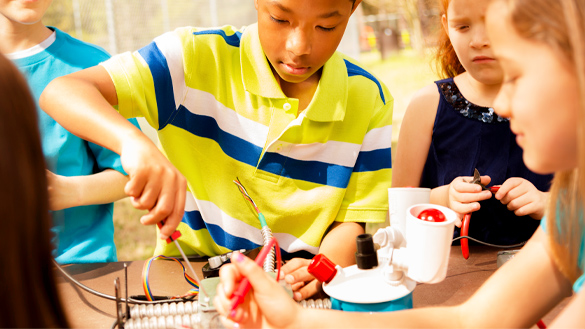 Three school children working on a robotic arm