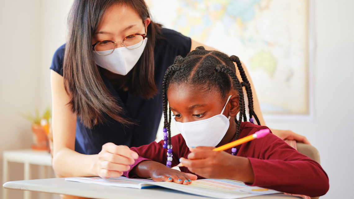 A teacher helping two students in a classroom