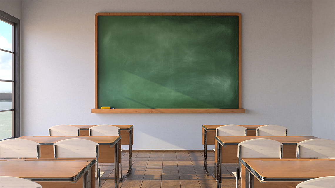 Green chalkboard, wooden desks and chairs in classroom