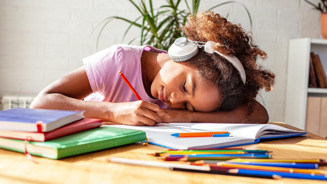 Girl writing intently in notebook within a classroom