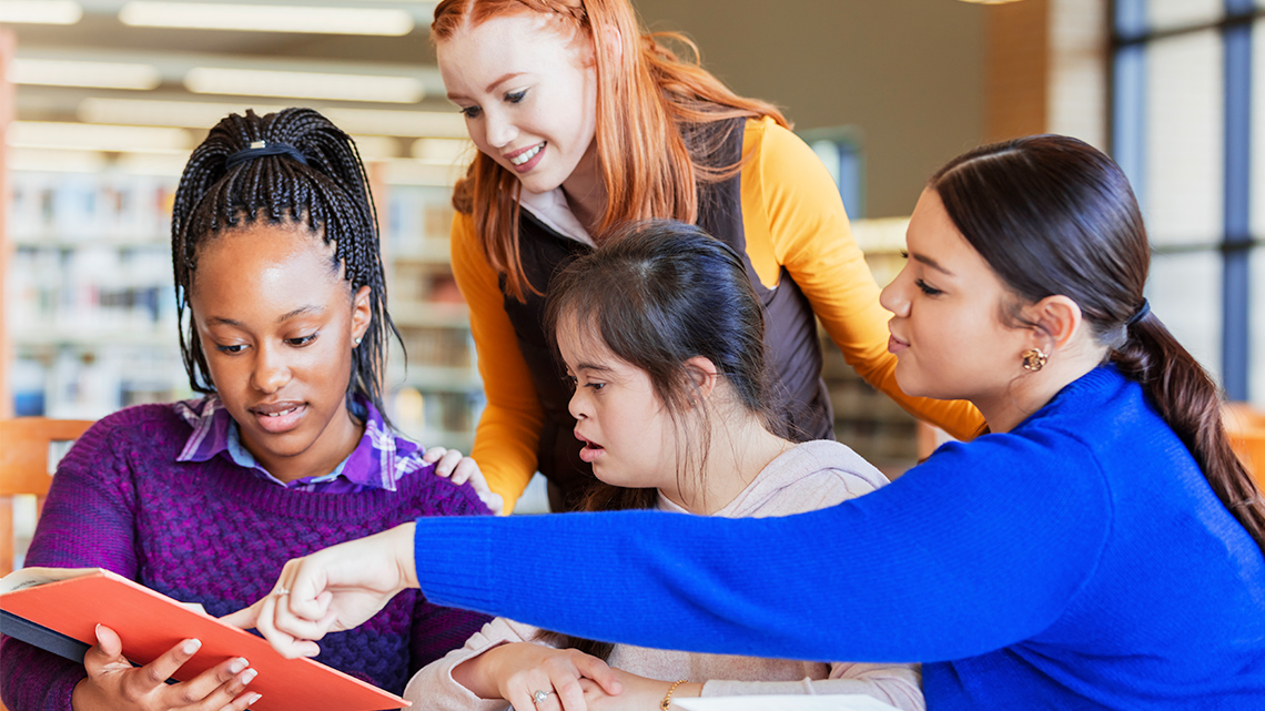 Image of students discussing a book.
