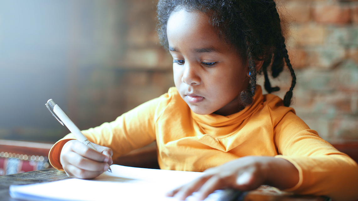 A Grade 1 kid writing in their notebook