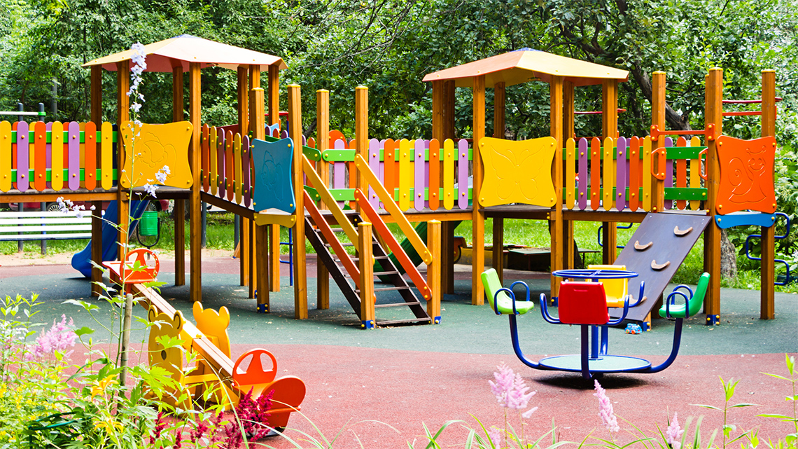 Playground structure with a picket fence that has a repeating colour pattern of pink,
                                orange, yellow.