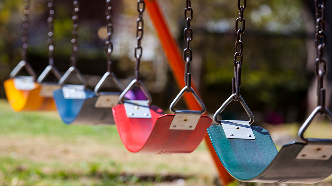 A set of 4 playground swings with seats in this colour order: yellow, blue, red and
                                green.