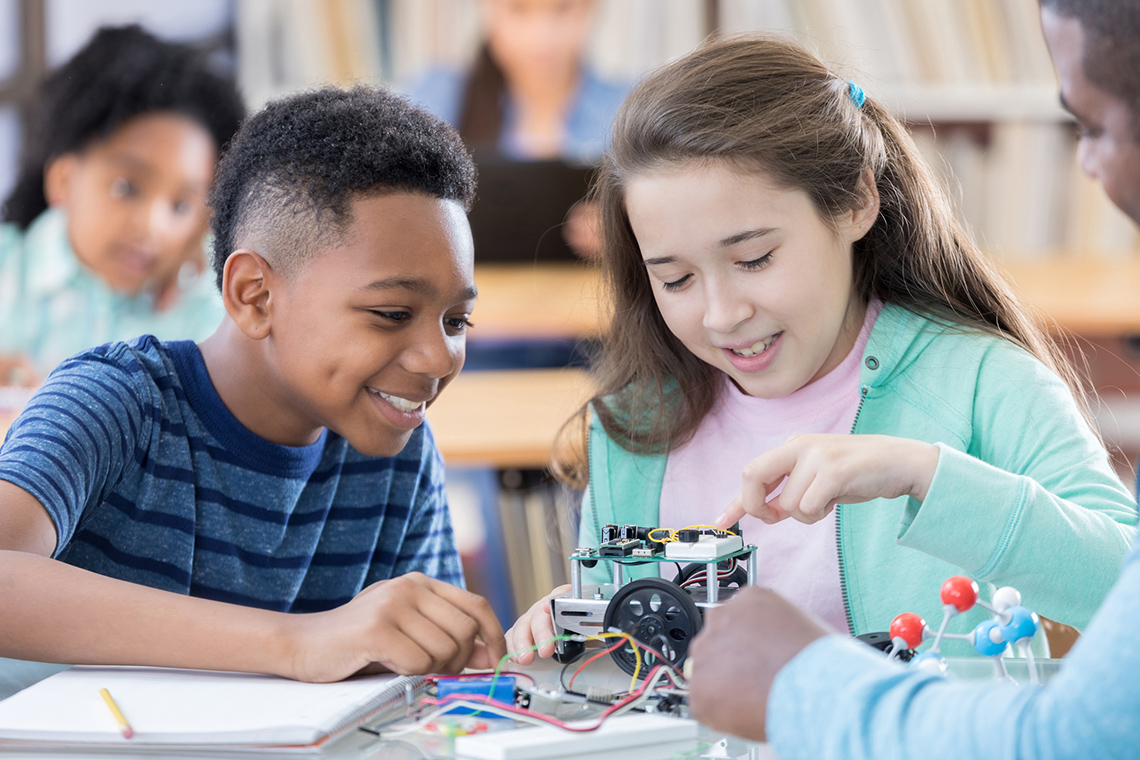 Children making a mini robot in a classroom.