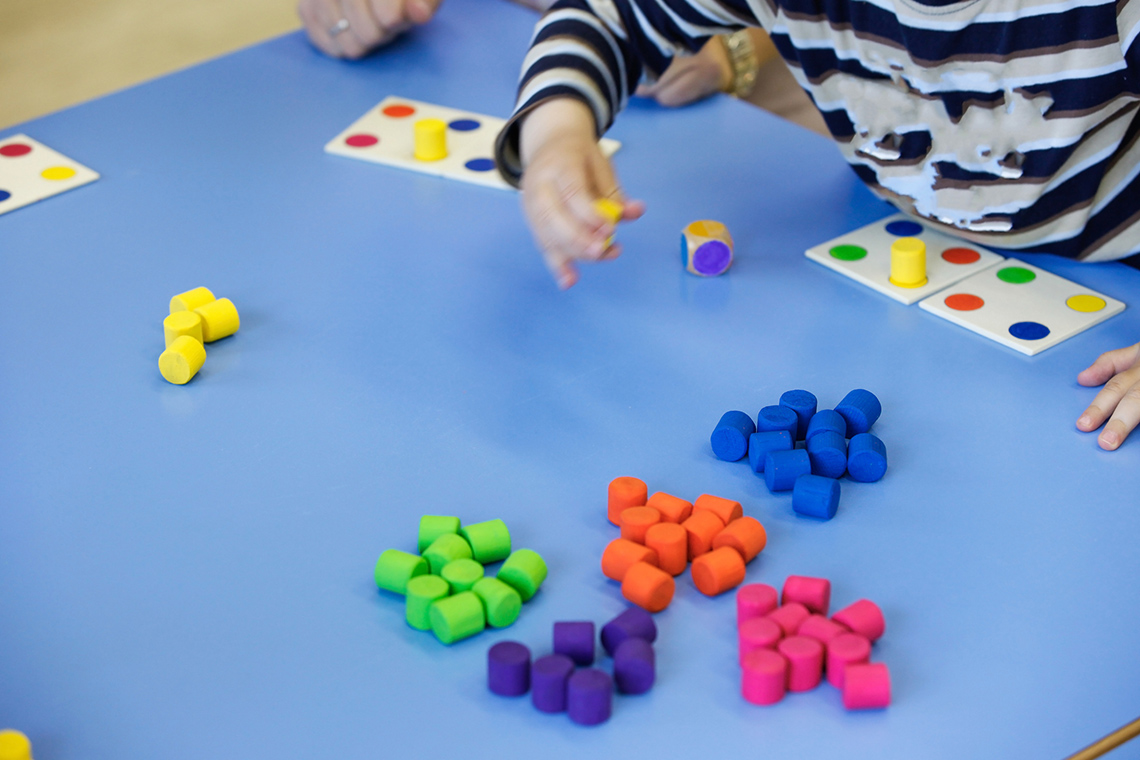 Sorting blocks by colour Child sorting blocks by colour; purple, orange, pink, blue, green, and yellow.
