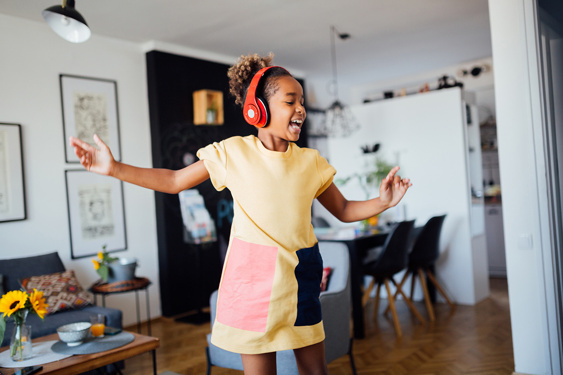 Child listening to music on headphones, while dancing.