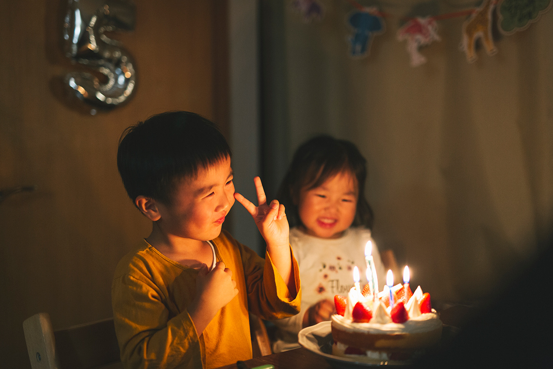 2 children celebrating a birth date with a cake.