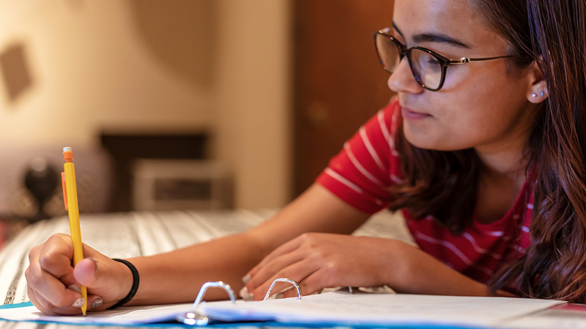 A student learning from home and typing their reflection on a laptop computer.