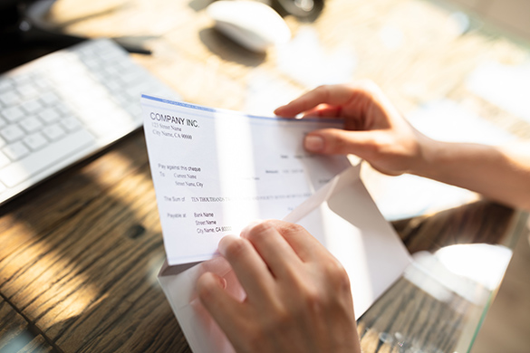 Person opening a paycheque from an envelope.