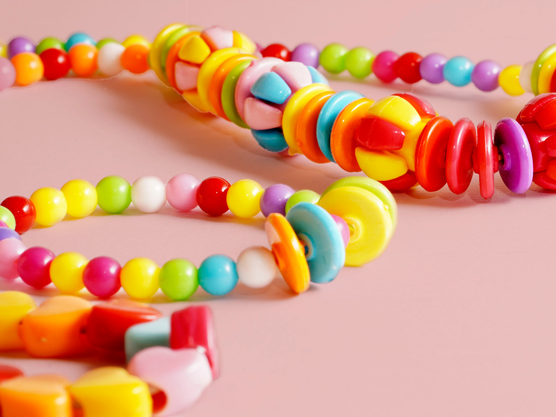 A beaded necklace and two beaded bracelets. The beads are multi-coloured. Some are large or small and round or flat.
