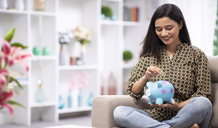 A young woman holding a white piggy bank.