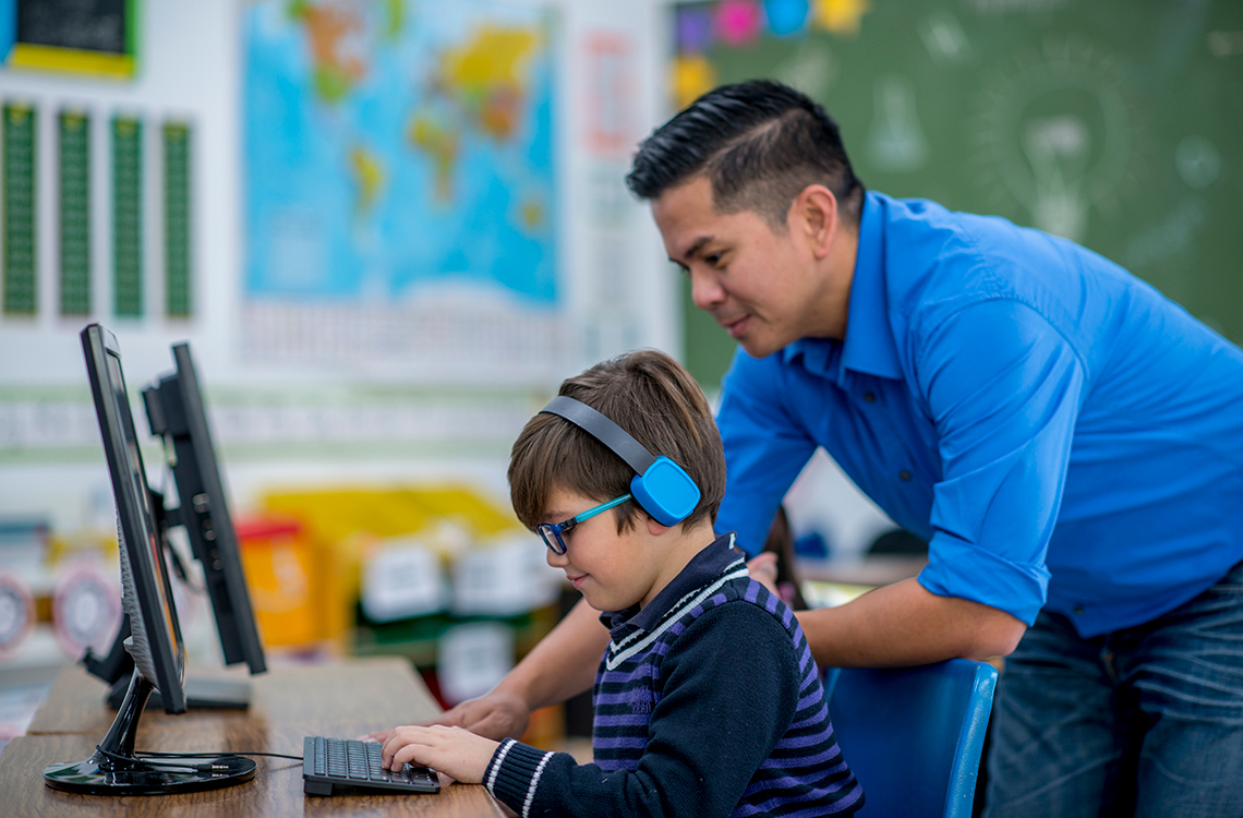 Student working on a computer with an adult supervising