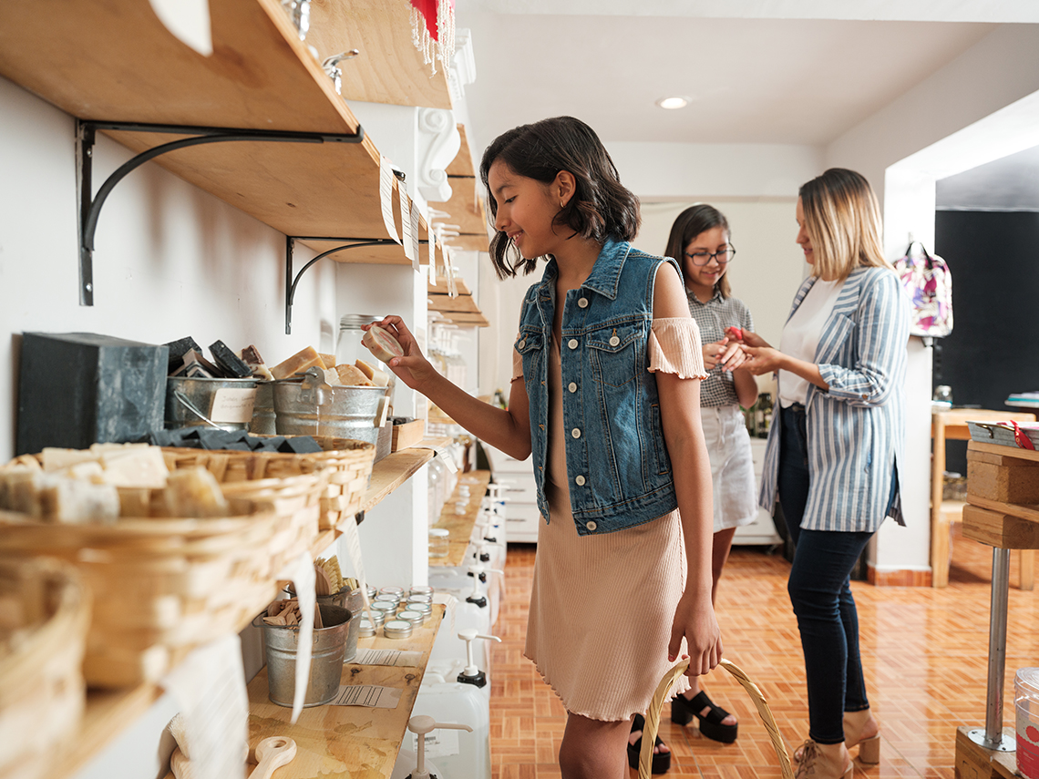 Three people browsing a variety of soaps available for sale at a store