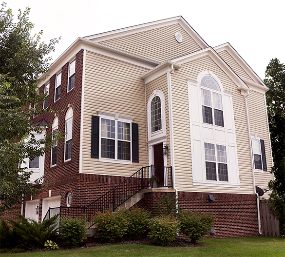 House B has many large windows, a garage, many stairs up to the front door, brick facing the street, and siding on the end