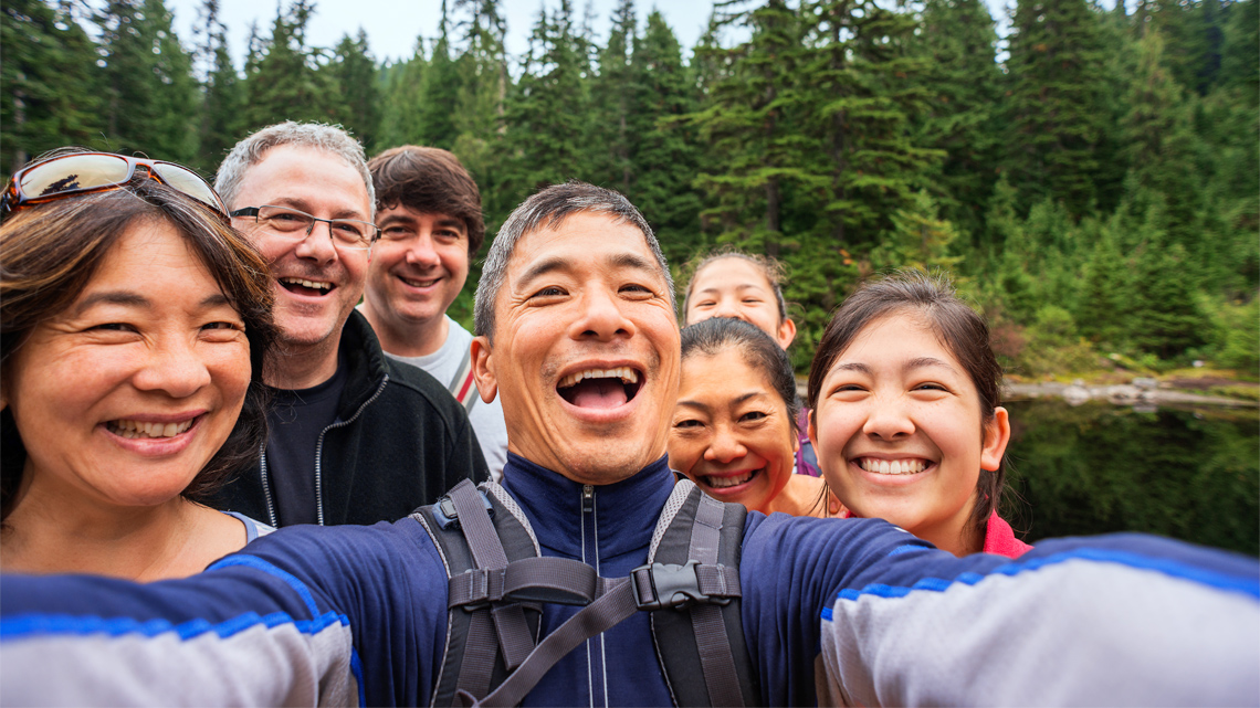 Seven family members pose for a selfie. The father is positioned in the centre.