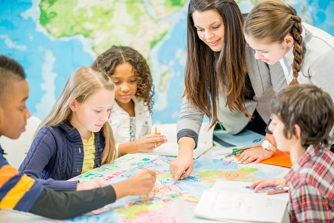 Group of children exploring a map on a table.