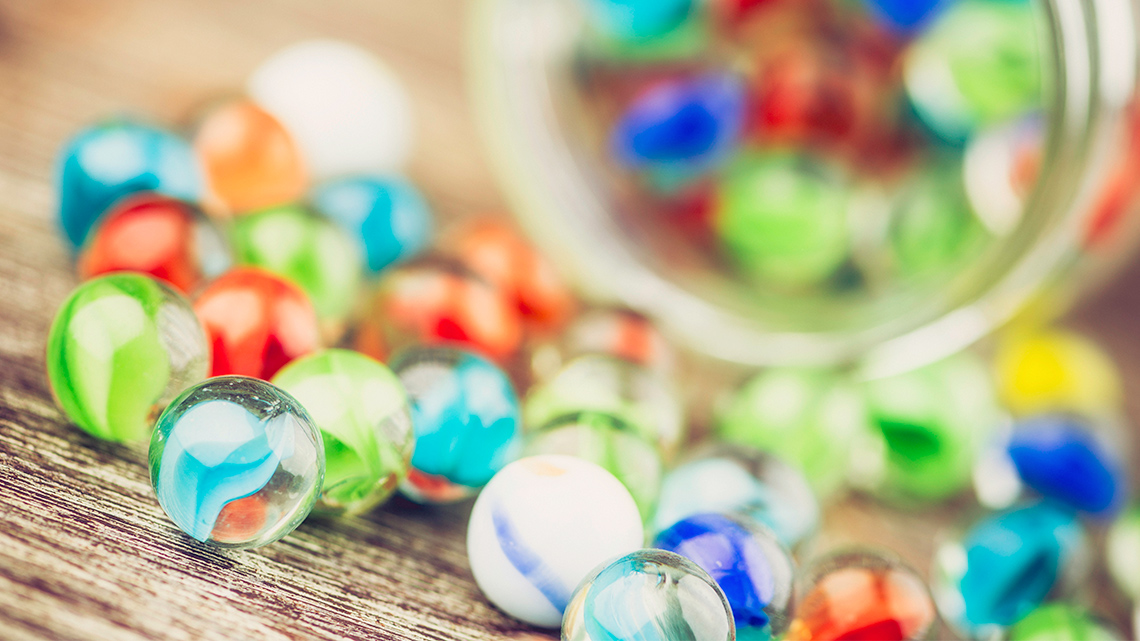 Open jar with colourful round marbles.