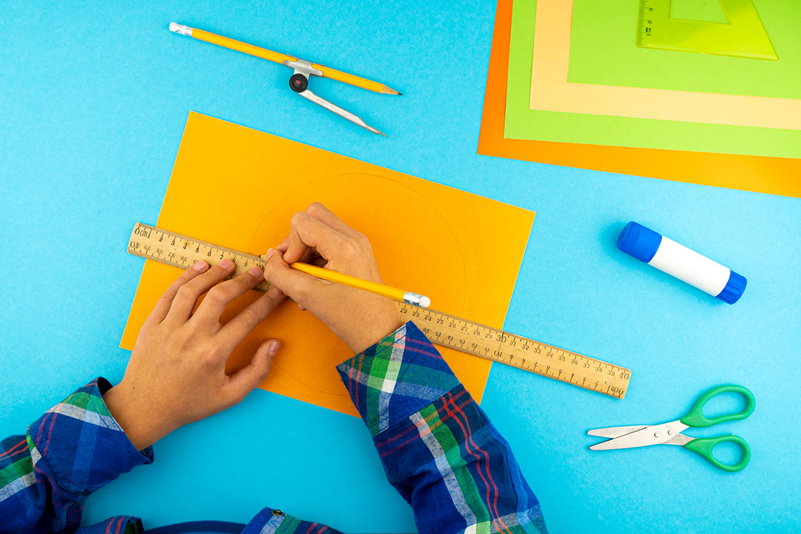 Measuring with a ruler Student holding a pencil while measuring with a ruler.