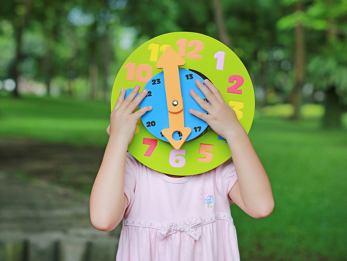 Student holding up a colourful paper round clock.