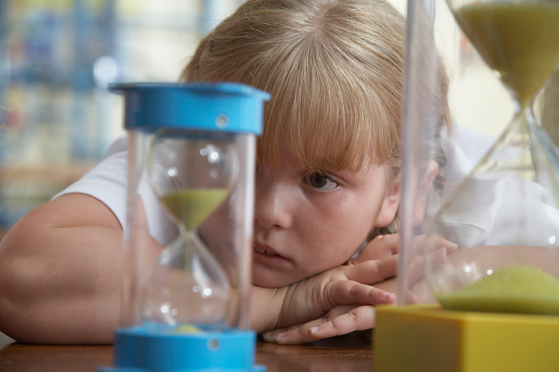Student observing the different sand timers on the desk in the classroom.