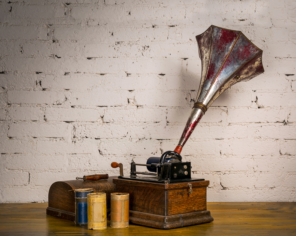 A graphophone, which is an old machine. The machine has a rectangular box as the base, cylinder
parts, and a cone on top.